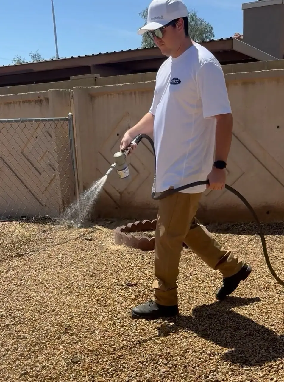 Plunto technician applying deodorizing treatment to a residential gravel yard